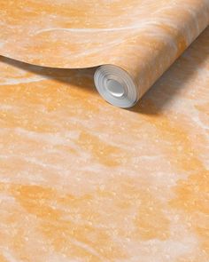 a roll of yellow marble paper on top of an orange surface with a white edge