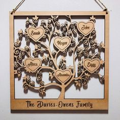 a wooden family tree hanging on the wall with names and hearts attached to it's sides