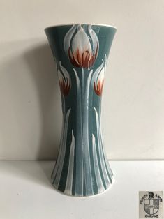 a vase with flowers painted on it sitting on a white counter top next to a wall