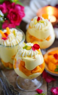 three desserts in small glass dishes on a table with flowers and candles behind them