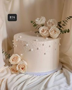 there is a wedding cake with white flowers on the top and pearls on the bottom