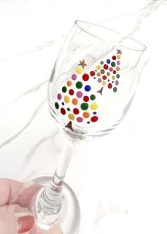 a hand is holding a wine glass with confetti on the bottom and stars in the middle