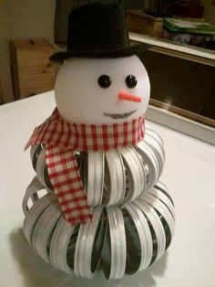 a snowman made out of duct tape on top of a white table with a red and black checkered scarf