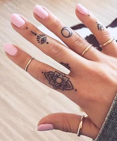 a woman's hand with two tattoos on her left and one on the right