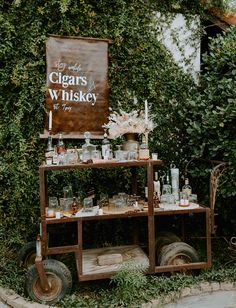 an old fashioned cart with liquor bottles and glasses on it in front of a sign