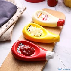 three plastic toys sitting on top of a wooden cutting board next to a measuring ruler