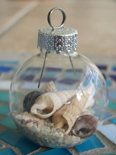 a glass ornament filled with shells on top of a blue and white tile floor