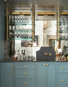 a blue cabinet with lots of glassware on top and gold trim around the edges