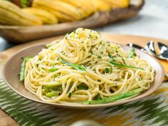 a plate of pasta with asparagus and parmesan cheese on the side