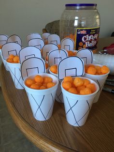 paper cups filled with oranges sitting on top of a table next to a jar of milk