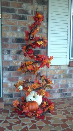 a small tree made out of leaves and pumpkins