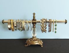 a gold jewelry rack with rings and bracelets hanging from it's sides on a blue wall