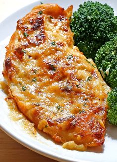 a white plate topped with chicken and broccoli on top of a wooden table