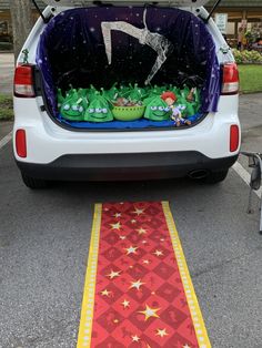 the back end of a white car with plants and decorations in it's trunk