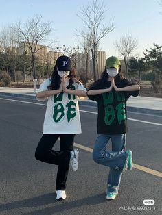 two people standing in the middle of an empty street with their hands up to their mouths