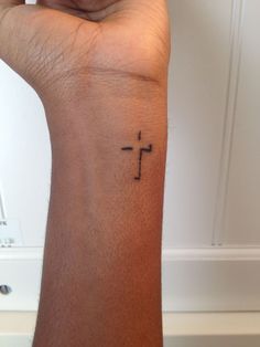 a small cross tattoo on the wrist