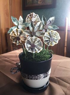 a potted plant made out of dollar bills sitting on top of a brown table