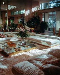 a living room filled with lots of white furniture and flowers on top of a coffee table