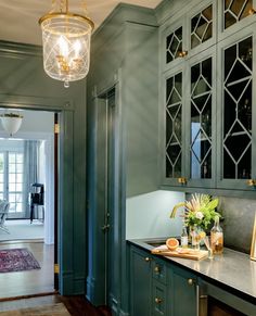 a kitchen with green cabinets and marble counter tops, gold accents on the door knobs