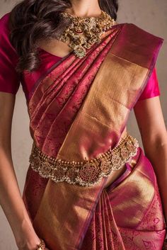 a woman in a red and gold sari with jewelry on her neck, posing for the