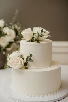 a three tiered white wedding cake with flowers on top