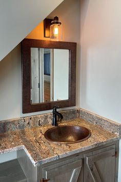 a bathroom sink under a large mirror next to a wooden cabinet with drawers and lights