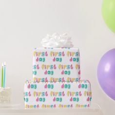 two wrapped presents sitting on top of a table next to balloons and birthday cake with candles