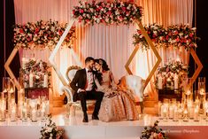 a bride and groom sitting on a chair in front of an altar with candles at their wedding