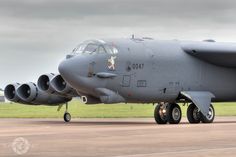 a large gray jet sitting on top of an airport tarmac next to a field