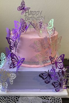 there is a pink cake with purple butterflies on it