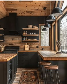 a kitchen with black cabinets and wooden counter tops in front of a large window that looks out onto the woods