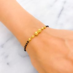 This upscale twin orb 22k gold bracelet, weighing 4.2 grams, showcases a stunning yellow gold finish with elegant black beads for a striking contrast. The bracelet measures 7 inches in length, featuring 0.6" adjustable links to ensure a perfect fit, all secured by a hook lock. Ideal for those who seek a sophisticated yet bold accessory, this piece beautifully combines the luxury of gold with the timeless appeal of black beads, creating a unique and fashionable statement. It's a versatile additio Traditional Gold Beaded Bracelet With Black Beads, Traditional Gold Bracelets With Black Beads, Elegant Gold Bracelets With Black Beads, Traditional Gold Bracelet With Black Beads, Gold Bracelets With Round Beads In 22k Gold, Gold Bracelet Jewelry With Black Beads, Gold Bracelet With Black Beads Jewelry, Black 22k Gold Jewelry With Round Beads, Gold Rosary Bracelet With Black Beads As Gift