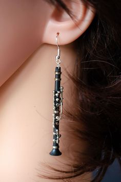 a close up of a person's ear with a musical instrument dangling from it