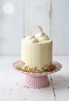 a cake on a pink plate with sprinkles and a rainbow topper