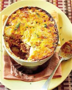 a yellow plate topped with a casserole covered in cheese and sauce next to a fork