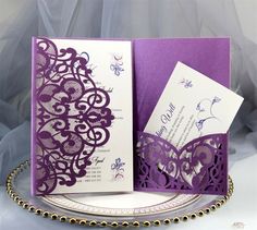 two purple and white wedding cards on a plate