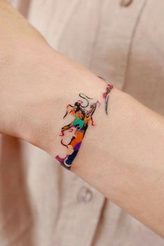 a woman's arm with a colorful tattoo design on the left side of her arm