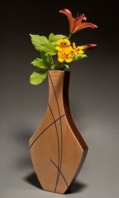 a wooden vase with flowers in it sitting on a gray surface and grey back ground