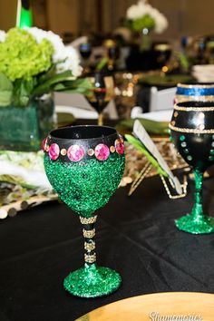 two goblets sitting on top of a table covered in black and green glitter