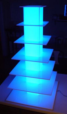 an illuminated shelf in the shape of a tower with blue lights on it's sides