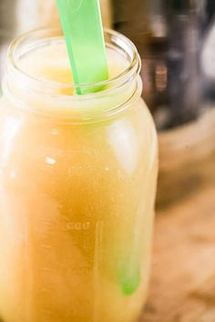 a mason jar filled with yellow liquid and a green straw