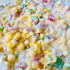 a bowl filled with corn and dressing on top of a table