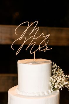 a white wedding cake with the word mr and mrs on top