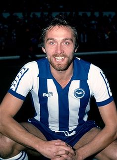 a man sitting on top of a soccer field wearing a blue and white striped shirt