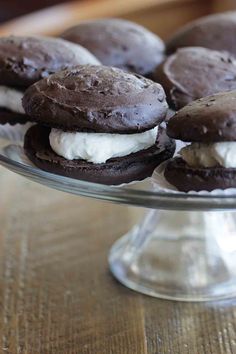 chocolate ice cream sandwiches on a glass cake plate with a wooden table in the background