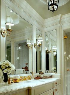 a white bathroom with gold accents and chandeliers