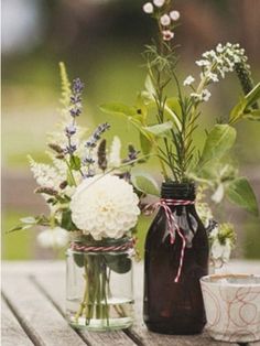 two mason jars with flowers in them sitting on a wooden table next to each other