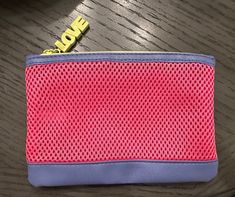 a pink and blue purse sitting on top of a wooden table