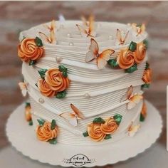 a three tiered white cake with orange flowers on the top and butterflies on the side