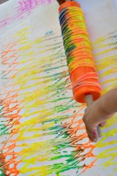 a child's hand is drawing with crayons on the paper that they are holding